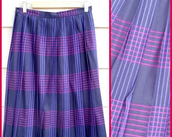 May include: A pleated skirt in a dark blue color with a plaid pattern of pink and purple stripes. The skirt is knee-length and has a simple design.