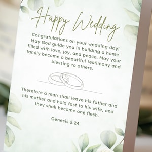 Può includere: Un biglietto di auguri di nozze con la scritta "Happy Wedding" in elegante calligrafia. Il biglietto presenta decorazioni floreali e a forma di foglie, con un messaggio sull'amore e la famiglia. La parte inferiore del biglietto recita "Wedding Blessing".