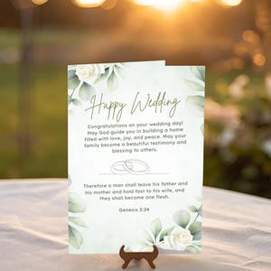 Puede incluir: Una tarjeta de boda con las palabras "Happy Wedding" en escritura elegante. La tarjeta presenta detalles florales y un versículo bíblico. Tamaño de la tarjeta: 12,7 cm x 17,8 cm.