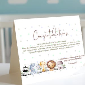 May include: A folded greeting card with the word "Congratulations" in a script font. The card features watercolor illustrations of a zebra, elephant, giraffe, lion, and hippo. The card size is 7" x 5".