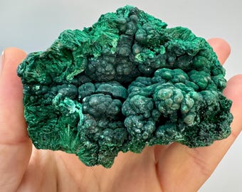 May include: A vibrant green malachite mineral specimen with a bubbly, textured surface. The mineral has a rich, dark green color with a crystalline structure. The malachite is a natural stone, often used in jewelry and decorative items.