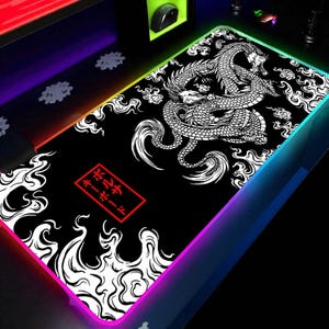 Peut inclure: Tapis de souris de jeu rectangulaire noir avec un motif de dragon blanc et du texte japonais dans un rectangle rouge. Le tapis a un bord LED coloré.