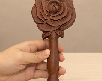 May include: A hand-carved wooden hairbrush featuring a detailed rose design. The brush has a dark brown finish, with the rose head and handle seamlessly integrated. The handle is smooth and rounded, providing a comfortable grip for styling.