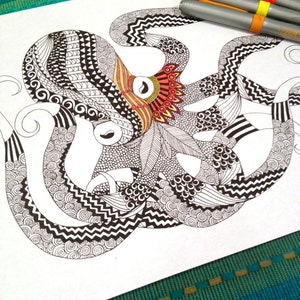 Puede incluir: Ilustración detallada en blanco y negro de un pulpo con patrones intrincados, incluyendo zigzags, espirales y puntos. El pulpo tiene acentos naranjas, rojos y amarillos. Tres bolígrafos grises con bandas de color descansan en la esquina superior derecha del papel.