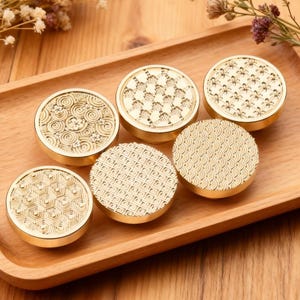 Könnte beinhalten: Ein Set aus drei Keramikbechern mit gesprenkelter, matter Oberfläche. Die Becher sind in Creme-, Hellgrau- und Dunkelgrautönen gehalten. Jeder Becher hat ein schlichtes, minimalistisches Design.
