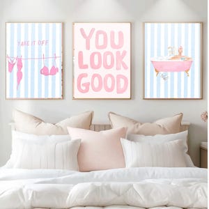 May include: Three framed art prints with a bedroom theme. One print says "Take it off" with pink lingerie on a clothesline. Another says "You Look Good" in pink. The third shows a pink bathtub with a person in it.