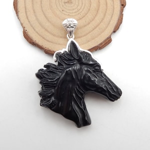 May include: Black horse head pendant carved from black onyx with a silver bail. The pendant is approximately 2 inches tall and 1.5 inches wide.