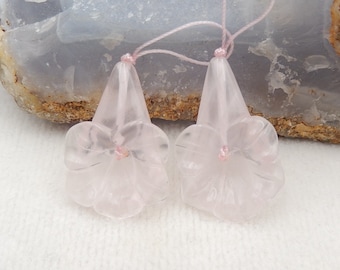 May include: Two pink rose quartz flower pendants with a light pink center. The pendants are strung on a thin pink cord.