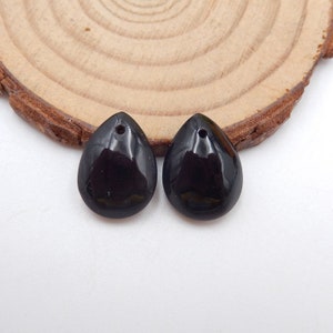 Puede incluir: Dos colgantes de piedra preciosa de forma de lágrima negra con un agujero en la parte superior para encordar.