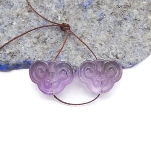 May include: A white ceramic mug with a black handle and the text "But First, Coffee" in a black, handwritten-style font. The mug is on a white surface.