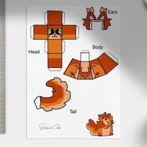 Könnte beinhalten: Ein Blatt Papier mit einem DIY-Fuchs-Design aus Papier. Der Fuchs ist orange und weiß, mit separaten Teilen für Kopf, Körper, Ohren und Schwanz. Ein Lineal befindet sich auf der linken Seite des Bildes.