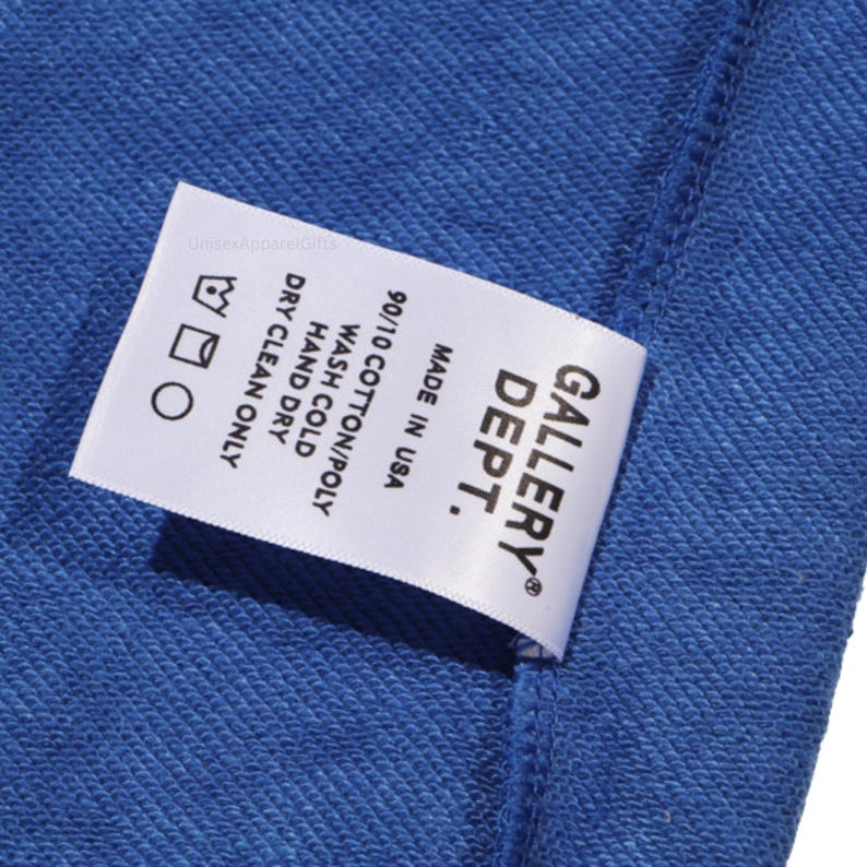 May include: A close-up of a blue fabric with a white tag. The tag reads "GALLERY DEPT." and includes washing instructions: wash cold, hand dry, and dry clean only. The fabric is made of 90/10 cotton/poly and made in the USA.