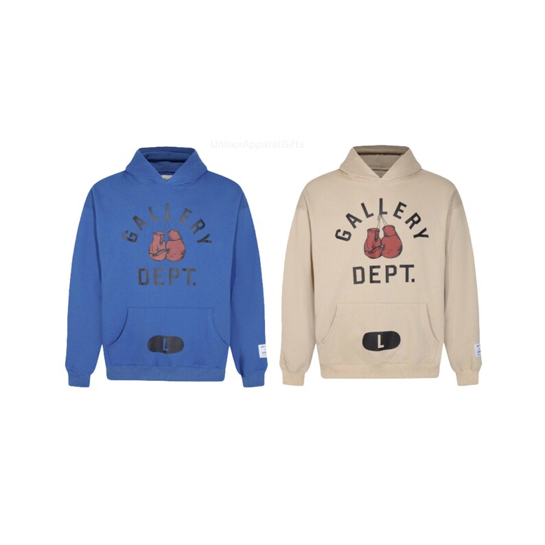 May include: Two hooded sweatshirts, one blue and one tan, featuring the text "GALLERY DEPT." above a pair of red boxing gloves. Each sweatshirt has a front pocket and a size indicator.