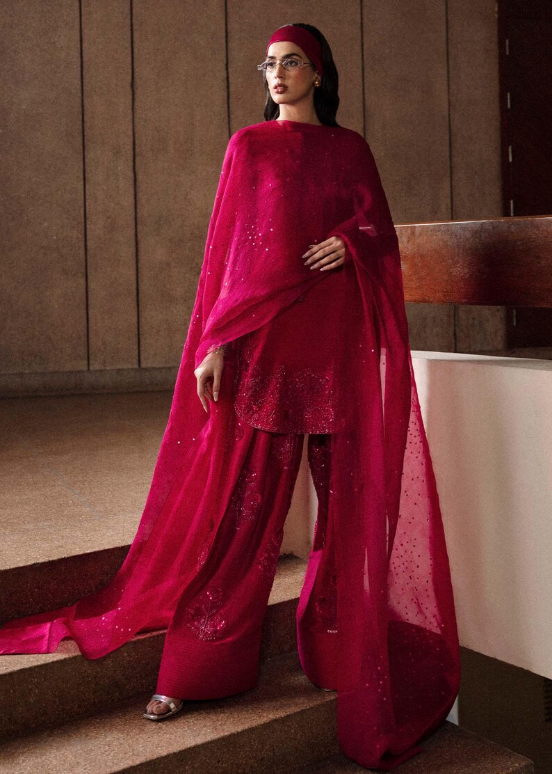 K&ouml;nnte beinhalten: Ein lebendiges fuchsiafarbenes Ensemble mit Tunika, weiten Hosen und einem flie&szlig;enden Schal. Das Outfit ist mit dezenten Pailletten verziert, und ein passendes Stirnband vervollst&auml;ndigt den Look. Geeignet f&uuml;r besondere Anl&auml;sse.