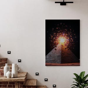 May include: A framed art print depicting a pyramid with a bright light emanating from its apex, surrounded by geometric shapes against a dark background. The pyramid is rendered in shades of gray and brown.