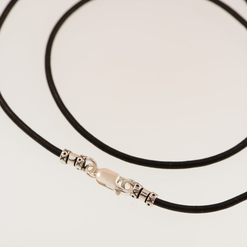 May include: A black leather cord necklace with a silver clasp and decorative beads.