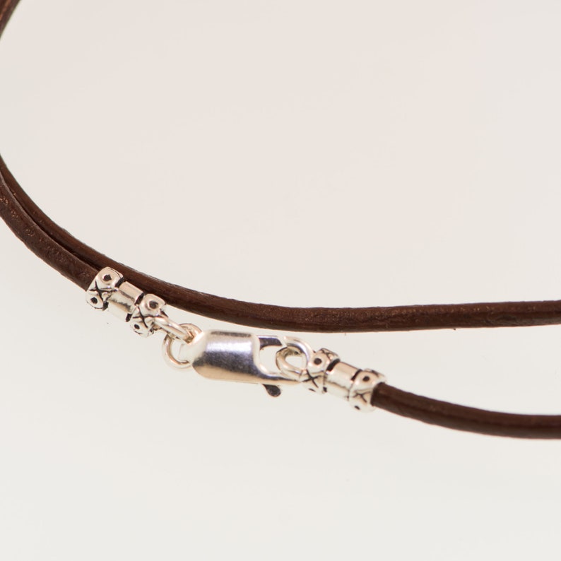 May include: A brown leather cord necklace with a silver clasp and decorative beads.