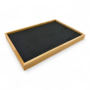 May include: A rectangular jewellery display tray with a light brown wooden frame and a black, textured interior. The interior has numerous small slots, likely for holding rings or other small jewellery items. The tray is empty.