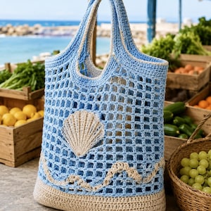 May include: A blue and beige crochet tote bag with a seashell design. The bag features a net-like pattern, a beige seashell applique, and a wave design. The handles and base are beige. The bag is designed for carrying items.