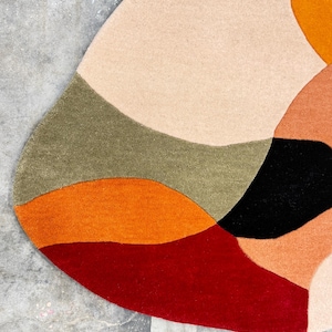Soft Hand Tufted Wool Rug – Contemporary Rust Red Beige Living Room Ru. 
Designer Abstract Rug – Hand Tufted Rust Beige Carpet for Modern HomesA colorful, abstract rug with a unique, organic shape. The rug features a palette of warm colors, including red, orange, peach, and beige, contrasted with black and olive green. The design is modern and eye-catching, suitable for various interior styles.