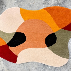 Large Hand Tufted Rug – Contemporary Rust Beige Abstract Design Carpet
Modern Luxury Rug – Rust, Beige & Red Hand Tufted Home Decor Rug. abstract rug with a freeform shape. The rug features a pattern of overlapping shapes in various colors, including orange, red, black, beige, and green. The rug is designed to be a decorative floor covering.