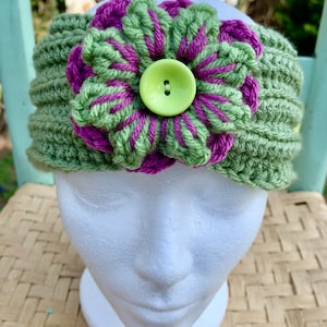 May include: Green crocheted headband with a purple and green flower and a lime green button.