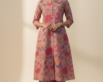 May include: A two-piece floral print outfit in shades of pink, red, and purple. The outfit includes a long-sleeved tunic with a mandarin collar and matching wide-leg pants. The floral pattern is detailed and covers the entire outfit.
