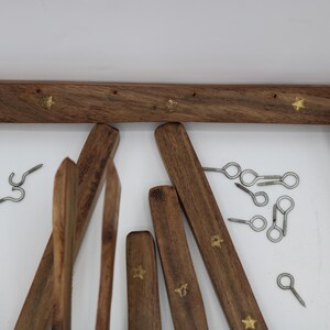 May include: Wooden ladder-style towel rack with brass star accents. Includes various wooden pieces, metal hooks, and screws. The rack is made of dark brown wood.