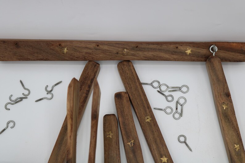 May include: Wooden ladder-style towel rack with brass star accents. Includes various wooden pieces, metal hooks, and screws. The rack is made of dark brown wood.
