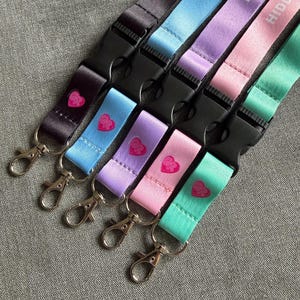 Puede incluir: Cinco cordones en negro, azul claro, lavanda, rosa y verde menta, cada uno con el texto HIDDEN DISCO, una hebilla de liberaci&oacute;n lateral de pl&aacute;stico negro y un mosquet&oacute;n de metal plateado. Un peque&ntilde;o coraz&oacute;n rosa est&aacute; impreso en cada cinta.