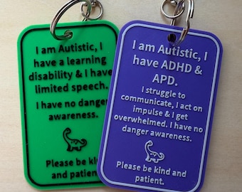 Puede incluir: Dos llaveros rectangulares con cierres de mosquetón metálicos. El verde dice: I am Autistic, I have a learning disability & I have limited speech. I have no danger awareness. Please be kind and patient. El morado dice: I am Autistic, I have ADHD & APD. I struggle to communicate, I act on impulse & I get overwhelmed. I have no danger awareness. Please be kind and patient.