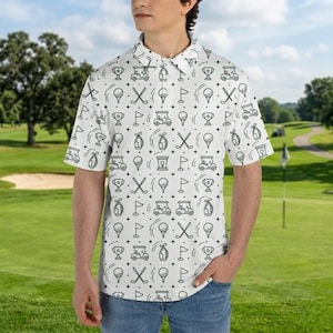 May include: White polo shirt with a repeating pattern of golf-themed icons in black. The design includes golf carts, golf balls, trophies, and crossed golf clubs. The shirt has short sleeves and a collared neckline.