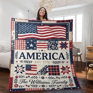 May include: A quilted blanket featuring an American flag design with red, white, and blue patches. The word "AMERICA" is prominently displayed, along with "EST. 1776" and "The Williams Family". The blanket has a patchwork design.