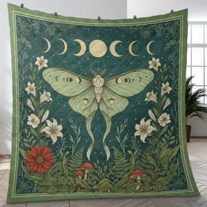 May include: A quilted blanket with a dark teal background featuring a large moth with moon phase details. The design includes white lilies, red flowers, mushrooms, and ferns, framed by a green border.