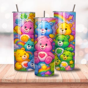 May include: Three stainless steel tumblers with colorful Care Bear designs. Each tumbler features a different Care Bear character, rainbows, and stars. The tumblers have a straw and a lid. The background is a blurred image of a wooden table.