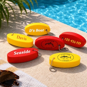 Pode incluir: Uma coleção de porta-chaves de espuma de formato oval em vermelho e amarelo, cada um com uma corrente de esferas de metal. Os porta-chaves exibem vários textos impressos, incluindo D's Boat, Davis, Seaside, 123-456-789 e dois logótipos personalizados.