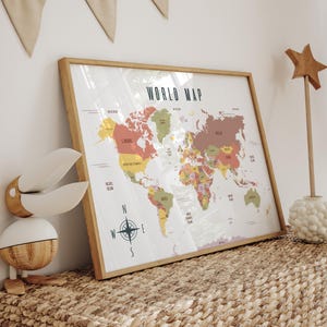 Pode incluir: Um mapa-múndi emoldurado com uma moldura de madeira. O mapa é colorido, com cada país em uma cor diferente. O título "WORLD MAP" está no topo. Uma rosa dos ventos está no centro inferior. O mapa está em uma superfície tecida.