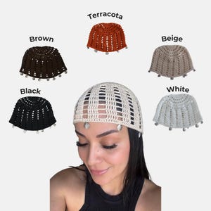 May include: A collection of five crochet skull caps featuring a repeating vertical stitch pattern and small silver-toned shell charms along the bottom edge. The caps are available in brown, terracotta, beige, black, and white color variations.