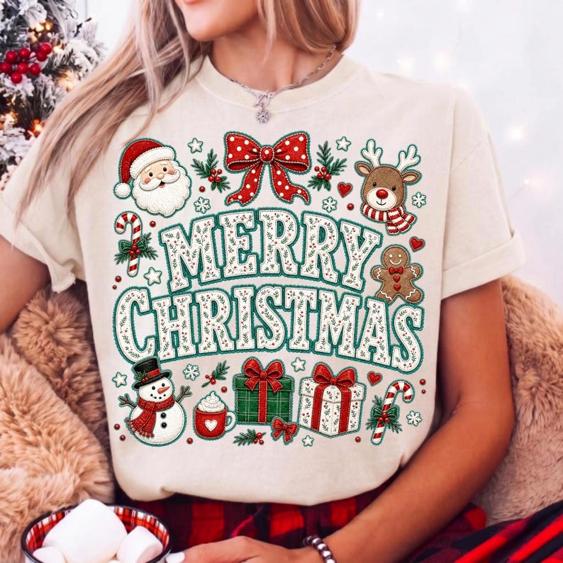 May include: A cream-colored t-shirt featuring a large graphic with the text MERRY CHRISTMAS in green and white. The design includes a Santa Claus, a reindeer, a gingerbread man, a snowman, a red bow, gift boxes, and candy canes.