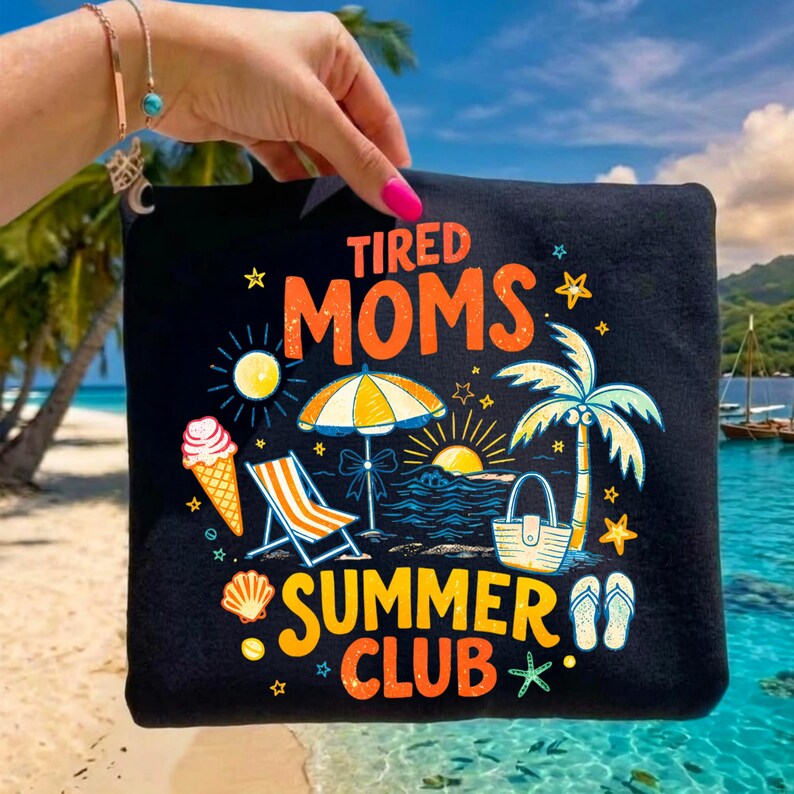 May include: Black tote bag with a colorful summer-themed graphic. The design includes the words "Tired Moms Summer Club" with illustrations of an ice cream cone, beach chair, umbrella, palm tree, and sunset.