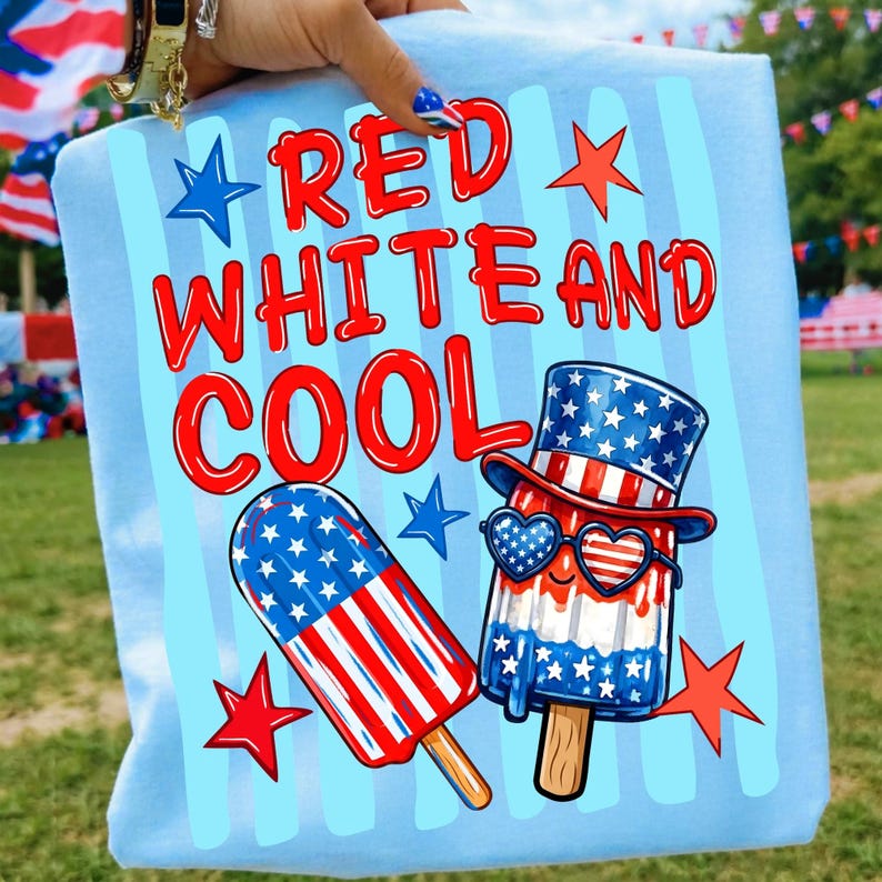 May include: A light blue t-shirt featuring the red text RED WHITE AND COOL. The graphic includes a popsicle with an American flag pattern and a second popsicle wearing a top hat and heart-shaped sunglasses, both decorated with stars and stripes.