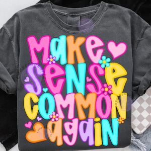 May include: Dark gray t-shirt with the phrase "MAKE SENSE COMMON AGAIN" in colorful bubble letters. The design includes hearts and flowers in pink, orange, yellow, and blue.