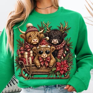Puede incluir: Una sudadera de cuello redondo verde brillante con un gr&aacute;fico de tres vacas Highland en un trineo de madera. Las vacas llevan gorros y bufandas de invierno, y una de ellas lleva gafas de sol. El dise&ntilde;o incluye regalos y ramas de pino.