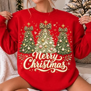 Peut inclure: Un sweat-shirt rouge &agrave; col rond orn&eacute; d'un motif repr&eacute;sentant trois sapins de No&euml;l verts d&eacute;cor&eacute;s de boules dor&eacute;es et roses, surmont&eacute;s de grands n&oelig;uds &agrave; imprim&eacute; l&eacute;opard. Le texte Merry Christmas est &eacute;crit en lettres cursives cr&egrave;me.