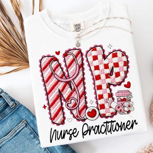 May include: White t-shirt with the letters "NP" in red and pink, featuring a stethoscope design. The shirt also includes the words "Nurse Practitioner" in black script, along with heart and star graphics.