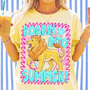 Puede incluir: Una camiseta de color amarillo p&aacute;lido con un gr&aacute;fico de un le&oacute;n rugiendo en el centro. El texto ROARIN INTO SUMMER est&aacute; impreso en letras azul brillante. El dise&ntilde;o incluye un borde rosa ondulado, estrellas azules y rosas, y detalles dorados.