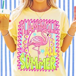 May include: A pale yellow t-shirt featuring a graphic of a pink flamingo centered within a pink scalloped border. The text reads FLAMINGLE ALL SUMMER in pink and lime green lettering, accented by small blue and yellow stars on a striped background.