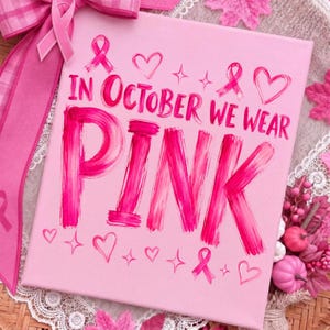 May include: A square pink canvas featuring the text IN OCTOBER WE WEAR PINK in bold, brush-stroke style lettering. The design includes small pink heart icons, four-pointed star accents, and pink awareness ribbons printed across the surface.