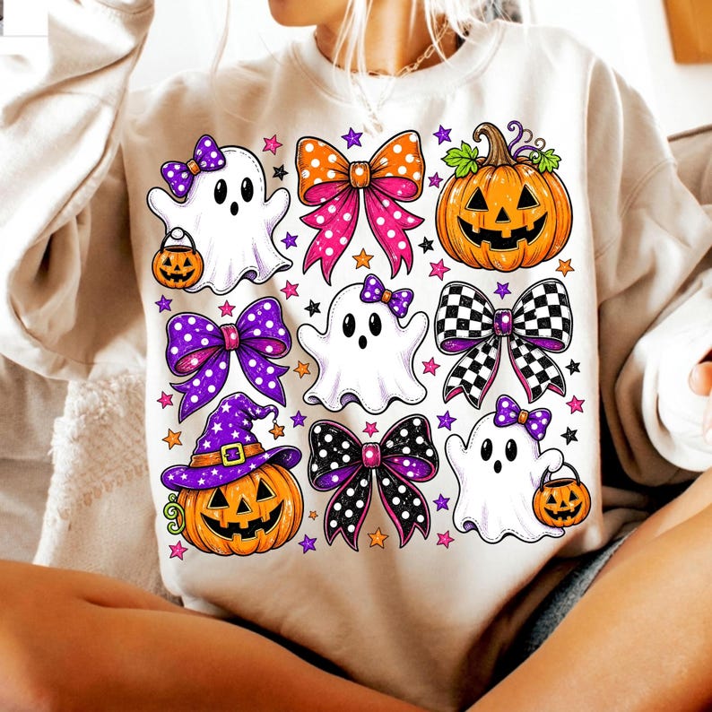 May include: A beige sweatshirt featuring a graphic print of three white ghosts, two orange jack-o'-lanterns, and four decorative bows in various patterns including polka dots and checkers, all accented with small colourful stars throughout the design.