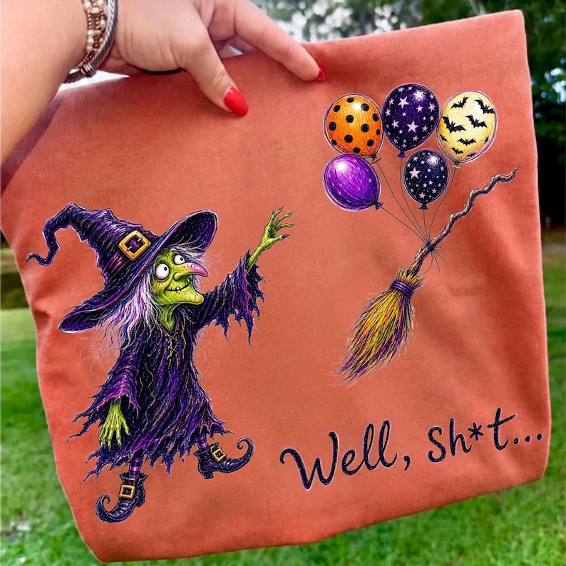 K&ouml;nnte beinhalten: Eine orangefarbene Tragetasche mit einer Grafik einer gr&uuml;nh&auml;utigen Hexe in violettem Gewand und Hut, die nach einem Besenstiel greift, an dem vier Luftballons mit orangefarbenen, violetten und schwarzen Mustern befestigt sind. Der Text "Well, sh*t..." ist schwarz gedruckt.